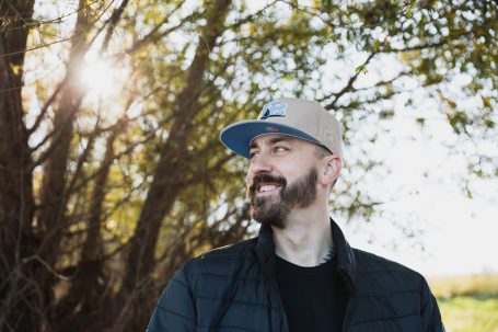 Männerportrait, Mann mit Cap vor einem Baumim Herbst, die Sonne scheint durch die Äste